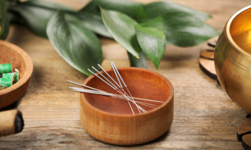 Bowl with acupuncture needles on wooden table